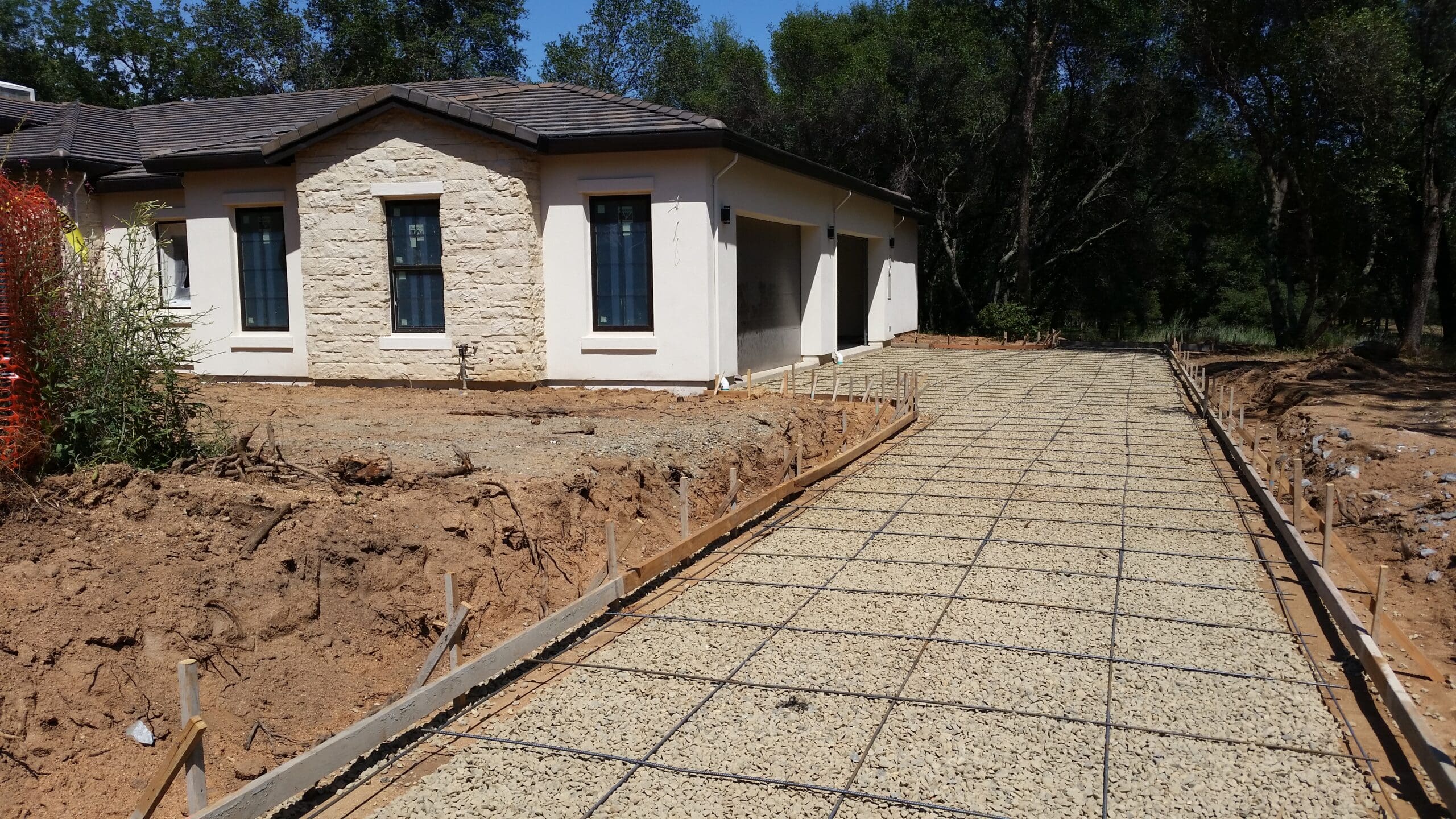 Custom home under construction in the Texas Hill Country with scenic oak trees and stone exterior