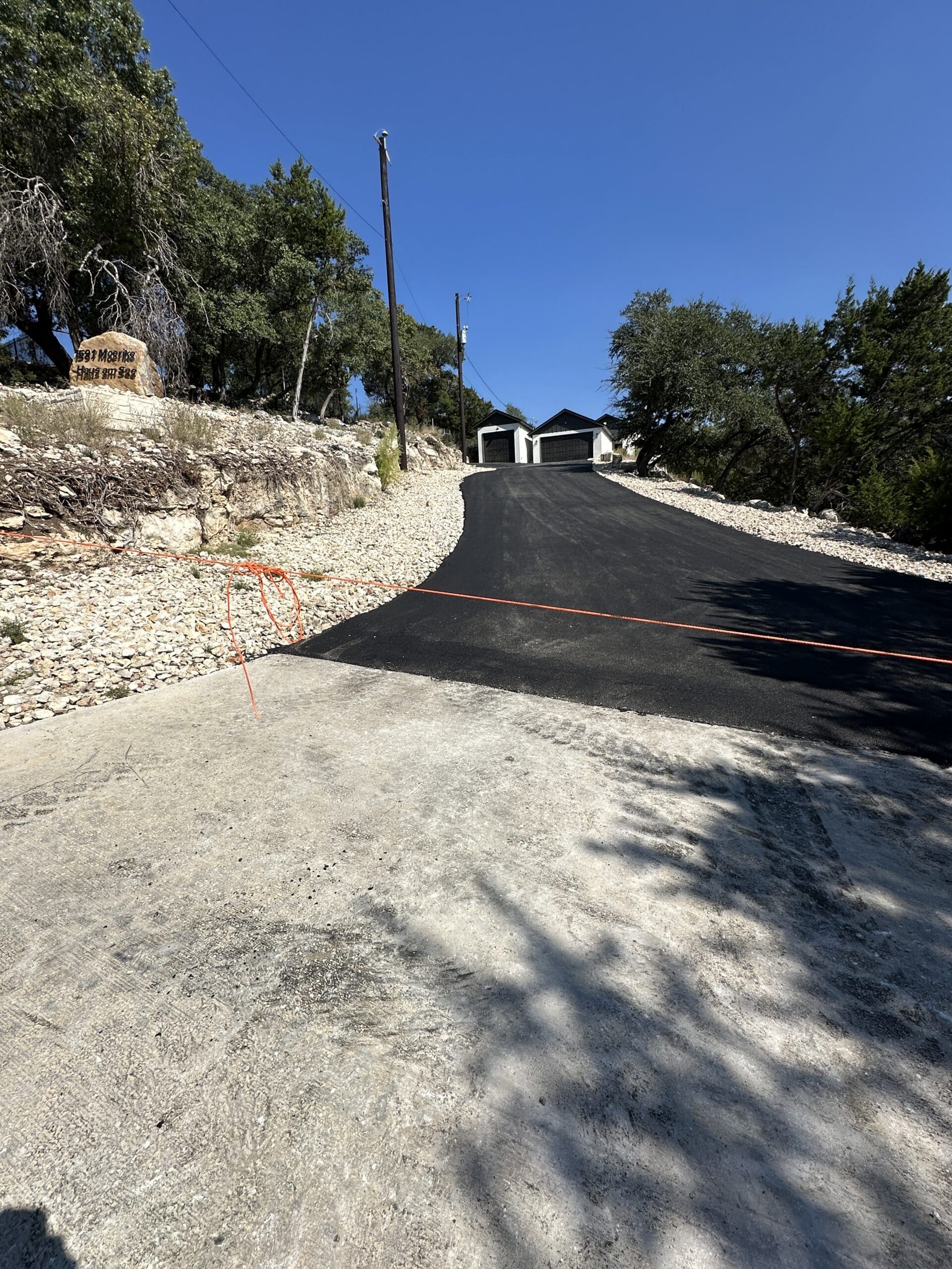 Long asphlt driveway leading to a custom home on a Texas Hill Country acreage lot